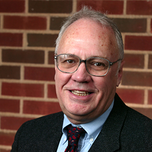 John Connett smiling in front of a brick wall